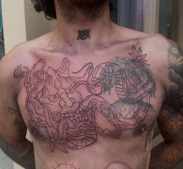 Large outlined chest tattoo with stylized creatures and flowing shapes, shown in progress.