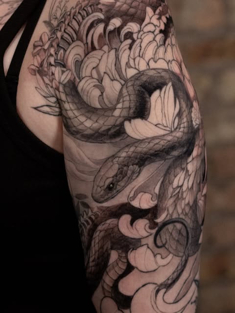 Black and grey snake and floral tattoo covering the upper arm.