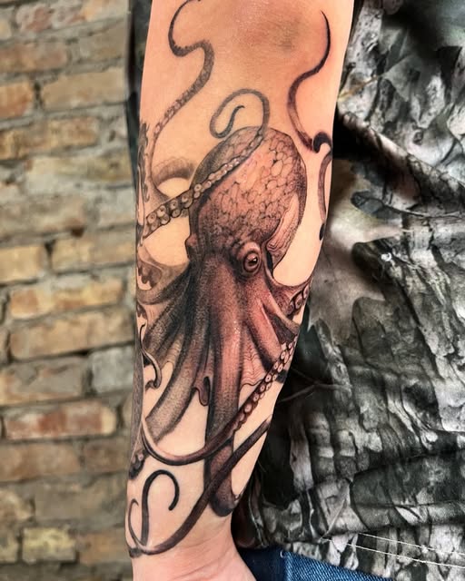 Black and grey octopus tattoo with curling tentacles on an arm.