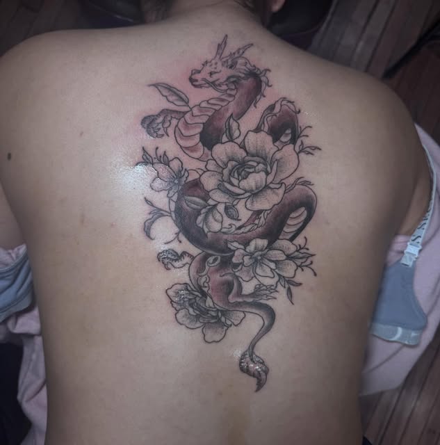 Dragon and flowers tattoo centered on the upper back.