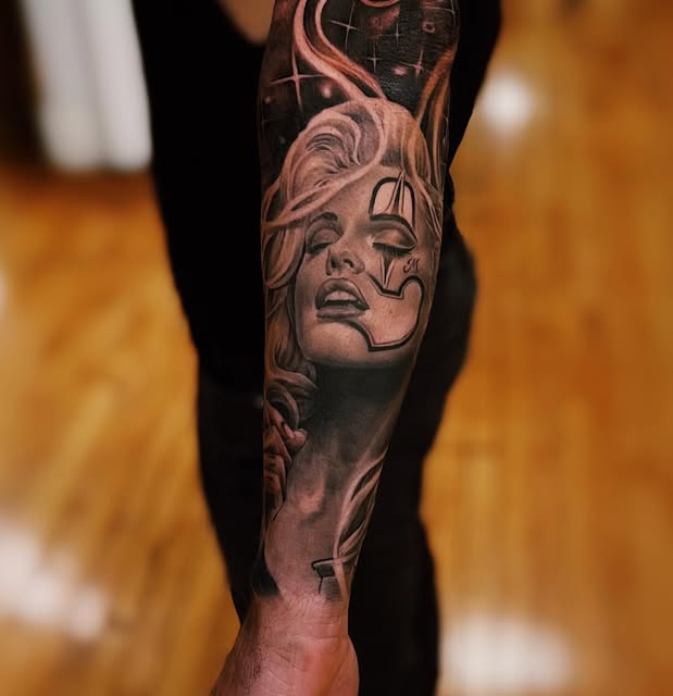 Black and grey portrait tattoo with flowing ornamental details on a lower leg.